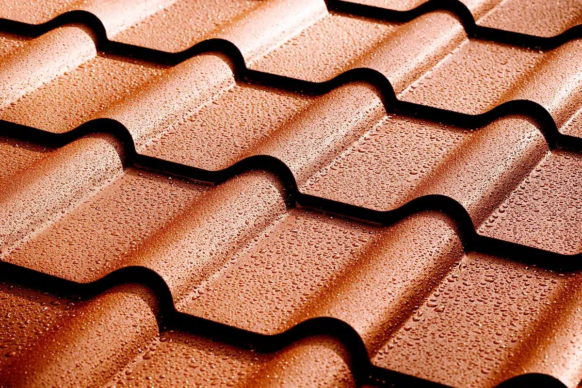 Toiture en tuiles métalliques couleur bronze, perlée de gouttelettes d'eau par milliers. Effet de surface protectrice et imperméable.